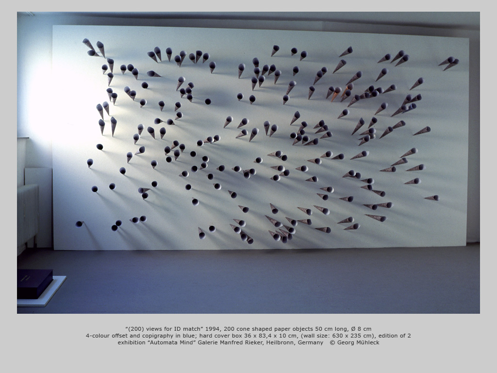 “(200) views for ID match” 1994, 200 cone shaped paper objects 50 cm long, Ø 8 cm 4-colour offset and copigraphy in blue; hard cover box 36 x 83,4 x 10 cm, (wall size: 630 x 235 cm), edition of 2 exhibition “Automata Mind” Galerie Manfred Rieker,